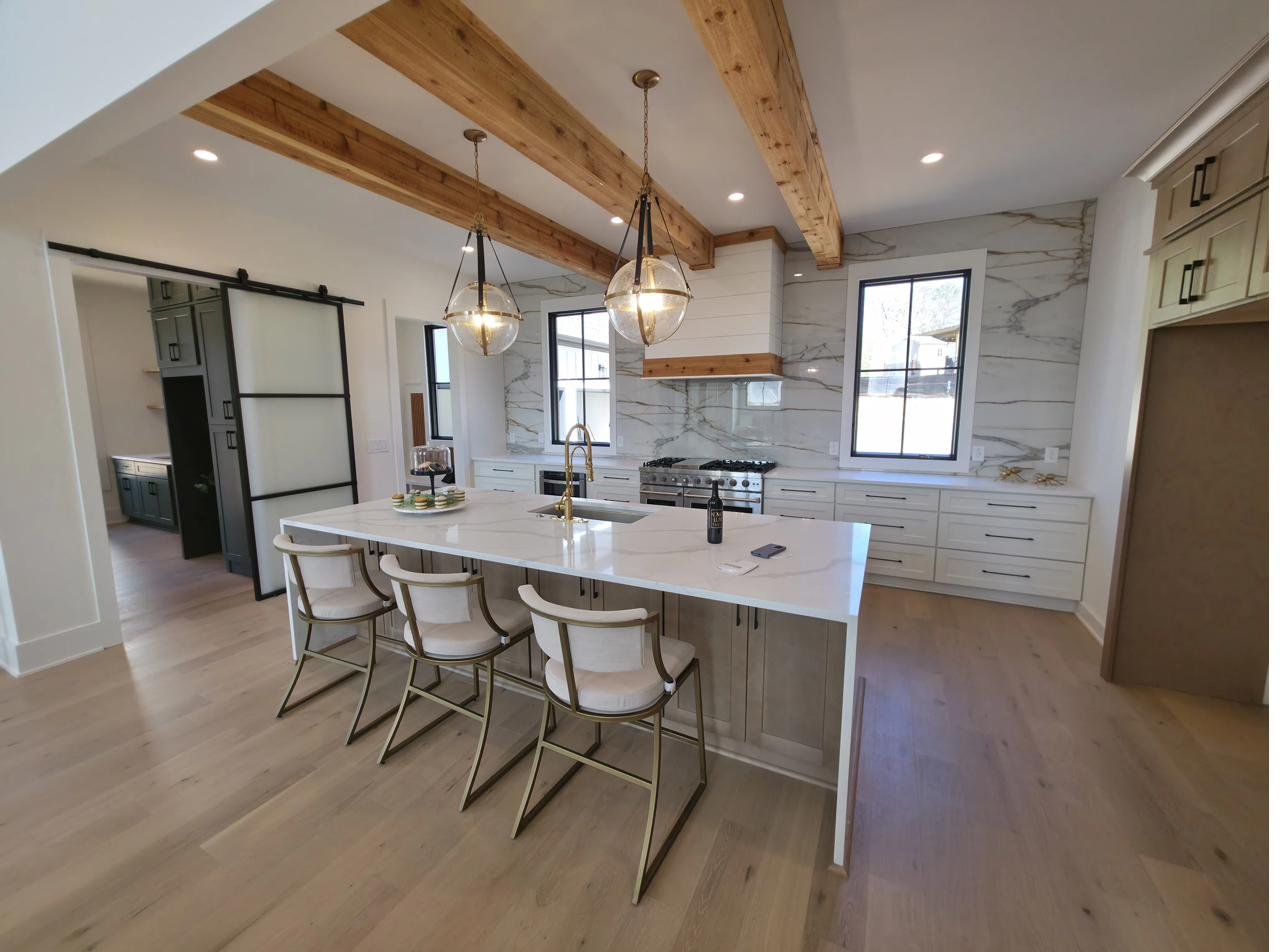 A finished kitchen with a beamed ceiling and a large center island