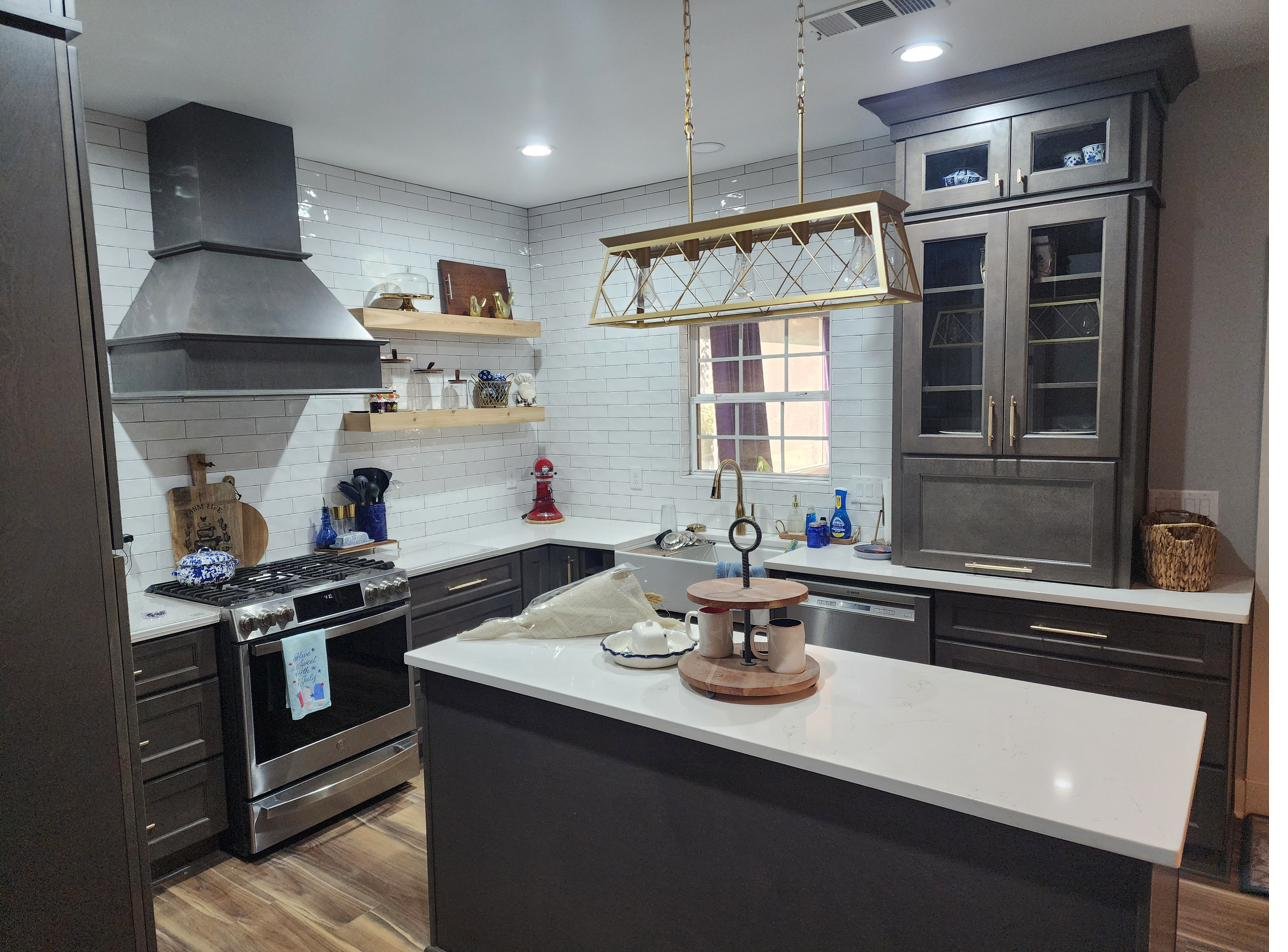 A navy island kitchen with marble countertops and glass-front cabinets