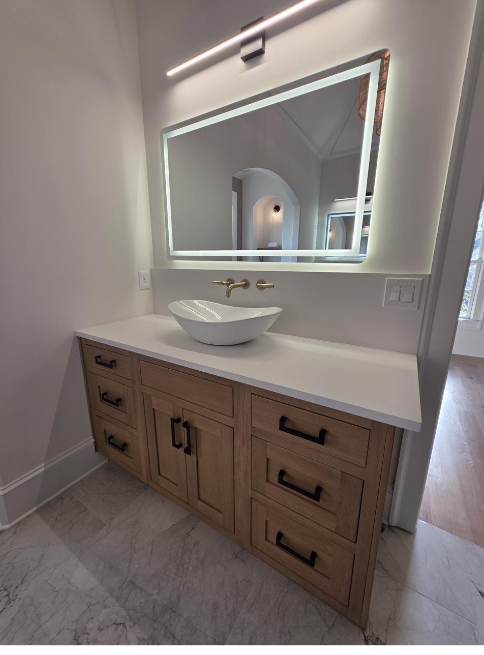 A single-sink bathroom vanity with a backlit mirror
